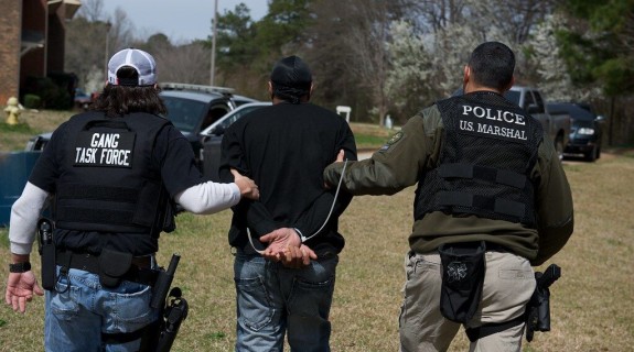 Two police officers escorting a handcuffed person