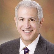 white male smiling in grey jacket and tie