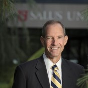 white man smiling in striped tie in black blazer