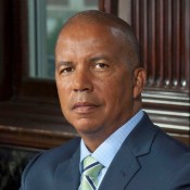 black man in green tie and grey blazer