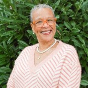 woman smiling in orange and white blouse wearing orange glasses