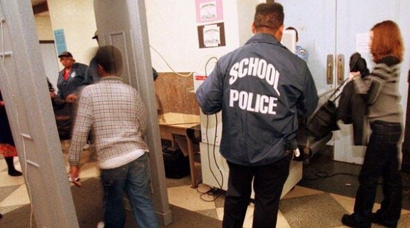 A student walking through a metal detector with school police nearby