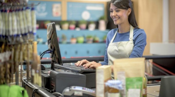 A white female cashier types on a register