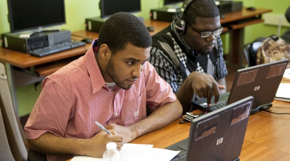 Two Black men working on laptops