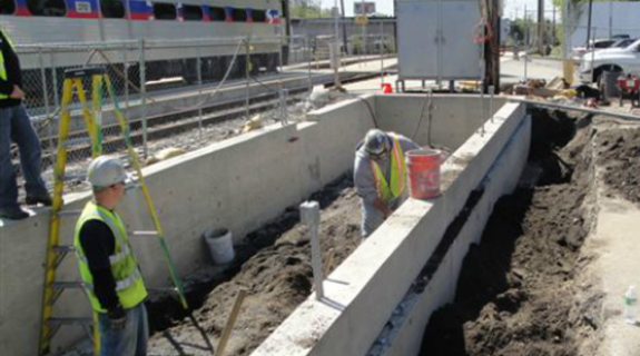 A construction worker working on a building foundation as another looks on