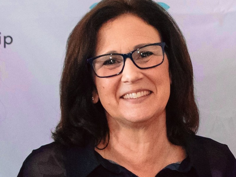 women smiling in glasses and black and blue blouse. 