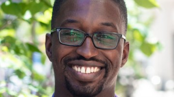 black man smiling in purple button down shirt